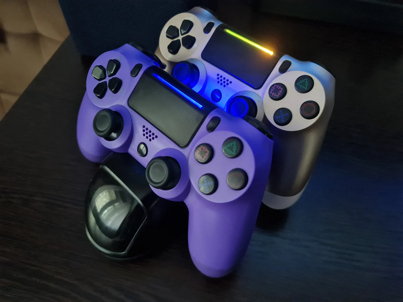 Два джойстика PS4 на зарядной станции Dobe с подсвеченными световыми панелями